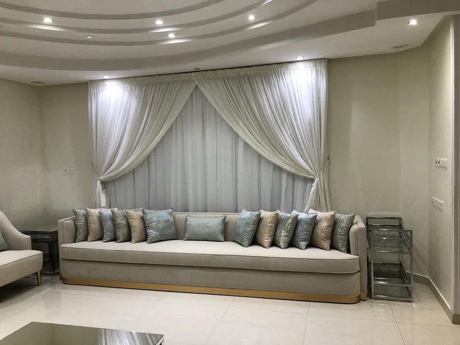 كنب بحواف ذهبية أمام ستارة شير